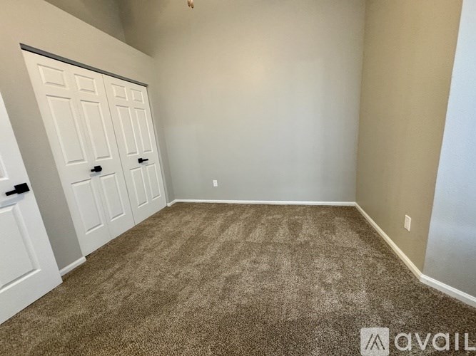A carpeted room with a white door and beige walls.