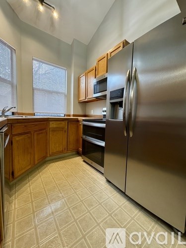 A kitchen with a stainless steel refrigerator and wooden cabinets.