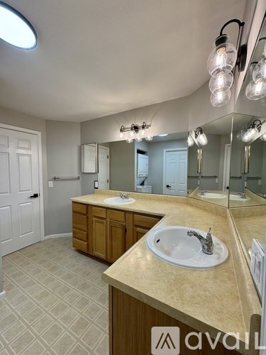 A bathroom with a sink, mirror, and lighting fixtures.