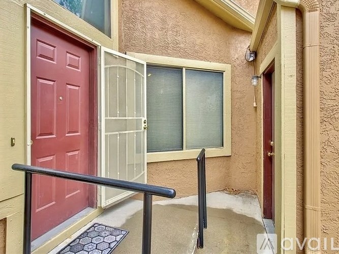 A red door is on the left and a window with blinds is on the right.