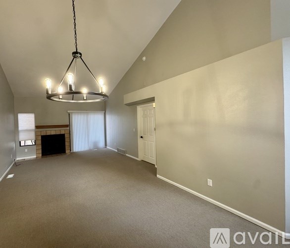 A large, empty room with a fireplace and a chandelier.