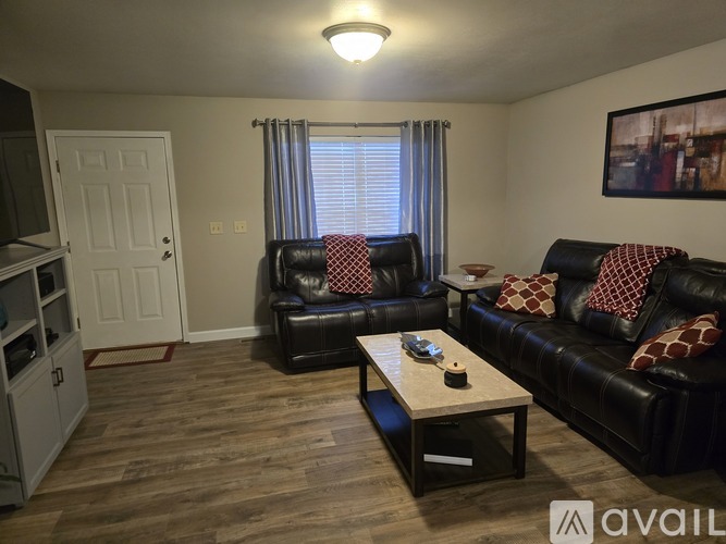 A living room with black leather couches and a wooden coffee table.