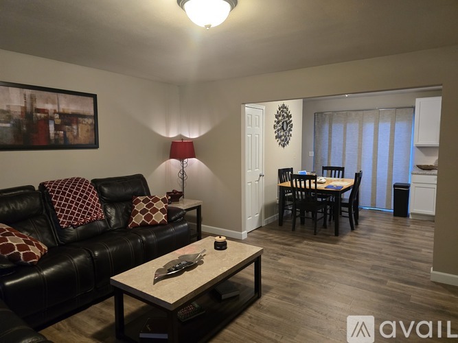 A living room with a black leather couch and a wooden coffee table.