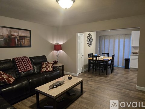 A living room with a black leather couch and a wooden coffee table.