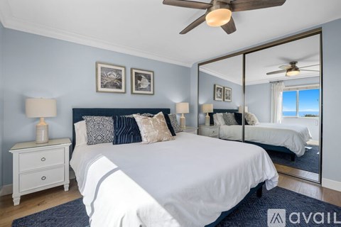 A bedroom with a large bed, a ceiling fan, and a mirror showing another room.