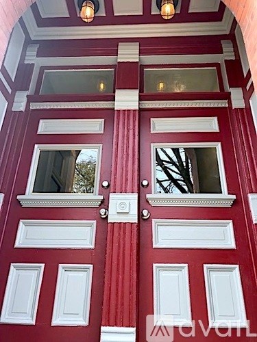 A red door with white trim and two windows.
