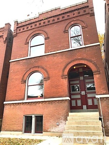 A red brick building with a large arched doorway and steps leading up to it.
