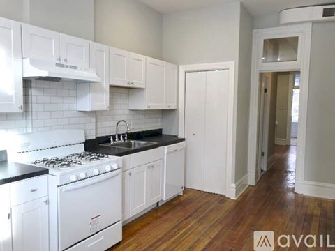 A kitchen with white cabinets and a black countertop.