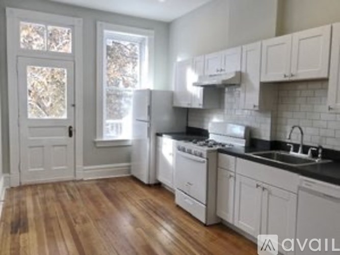 A kitchen with white appliances and wooden floors.