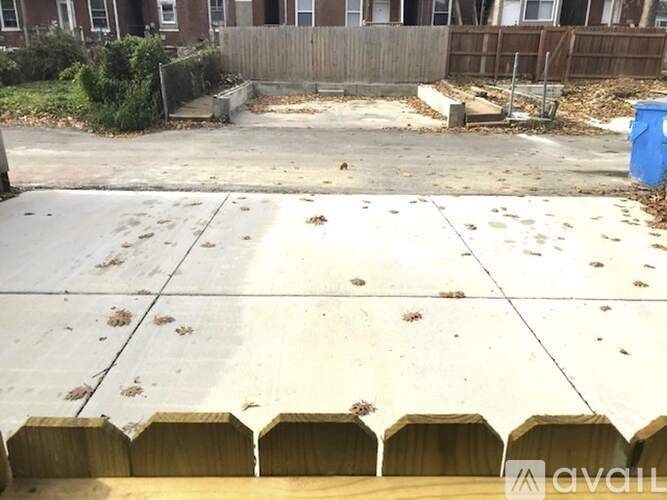 A blue trash can sits on a sidewalk.
