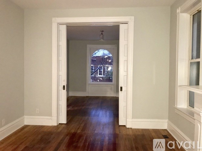 A room with a wooden floor and a doorway leading to another room.