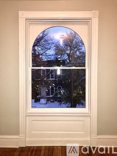 A window with a view of a snowy street at night.