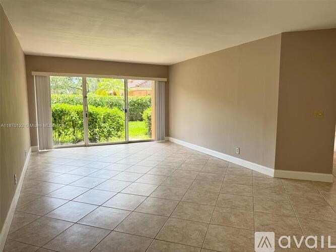 A spacious room with tiled flooring and sliding glass doors leading to a garden.