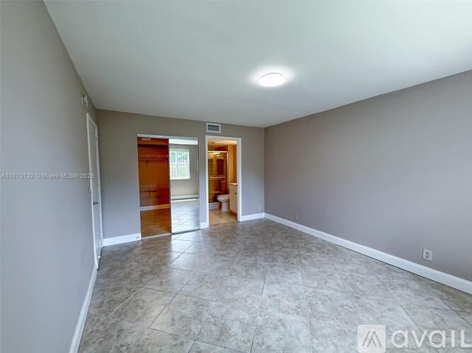 A room with a tiled floor and a door leading to another room.