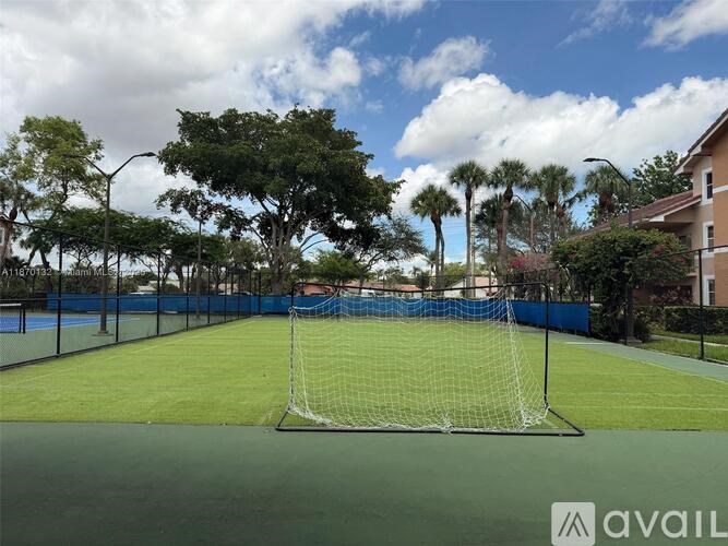 A tennis court with a blue fence and trees in the background.