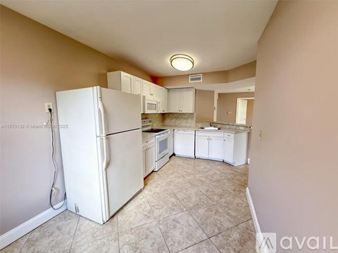 A kitchen with a white refrigerator and cabinets.