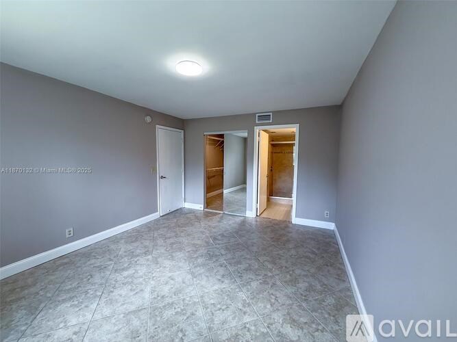 A room with grey walls and a tiled floor is available for rent.