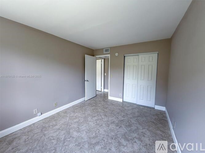 A room with a carpeted floor and two doors.