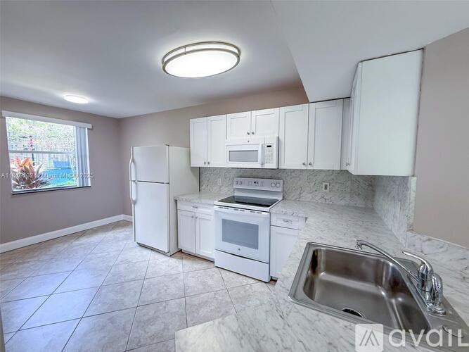 A kitchen with white appliances and a marble countertop.