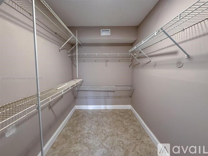 A walk-in closet with shelving and a tile floor.