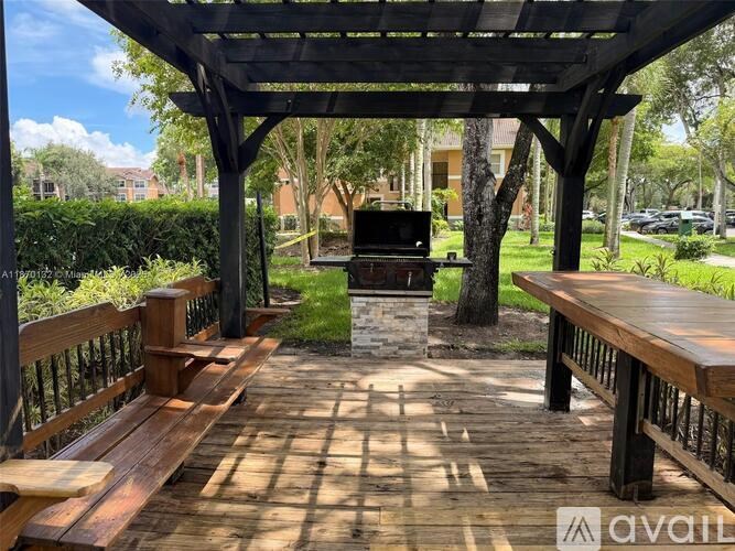 A wooden pavilion with benches and a grill in the middle of a park.