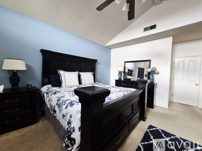 A bedroom with a large bed and a ceiling fan.