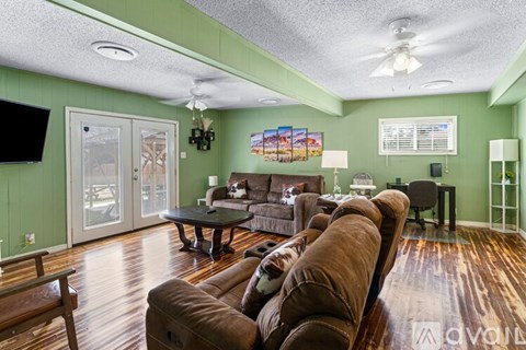 A living room with a brown couch and a television on the wall.