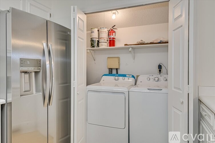 A kitchen with a refrigerator, washing machine, and dryer.
