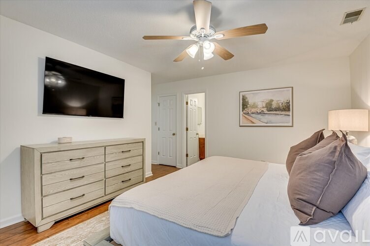 A bedroom with a bed, dresser, and ceiling fan.