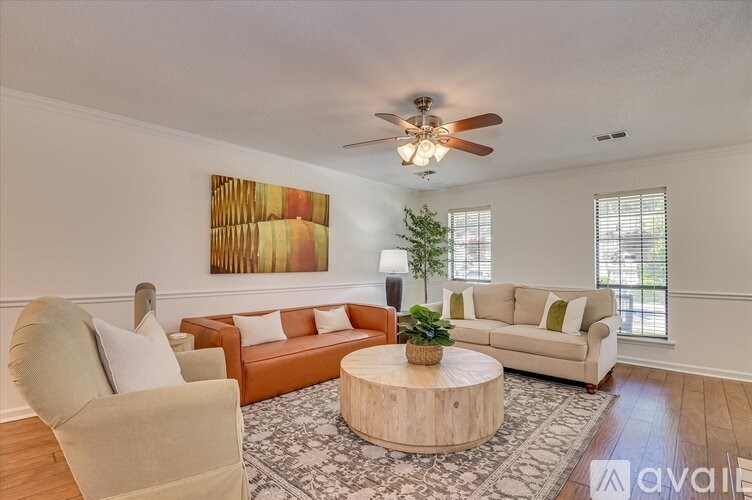 A living room with a round coffee table and a painting on the wall.