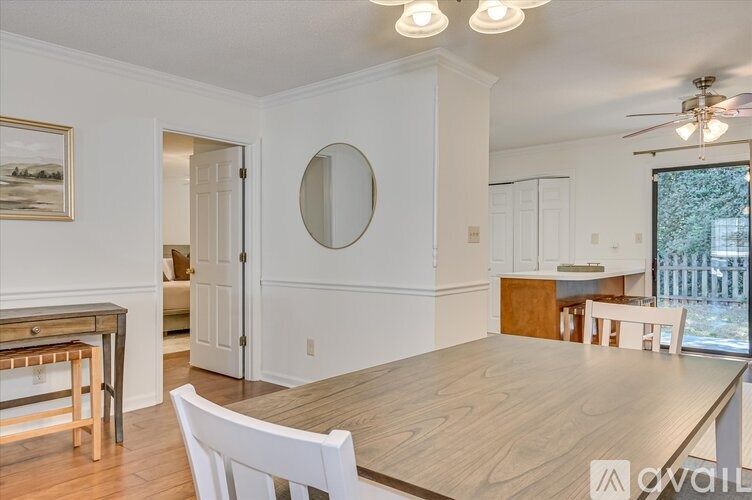 A dining room with a wooden table and white chairs.