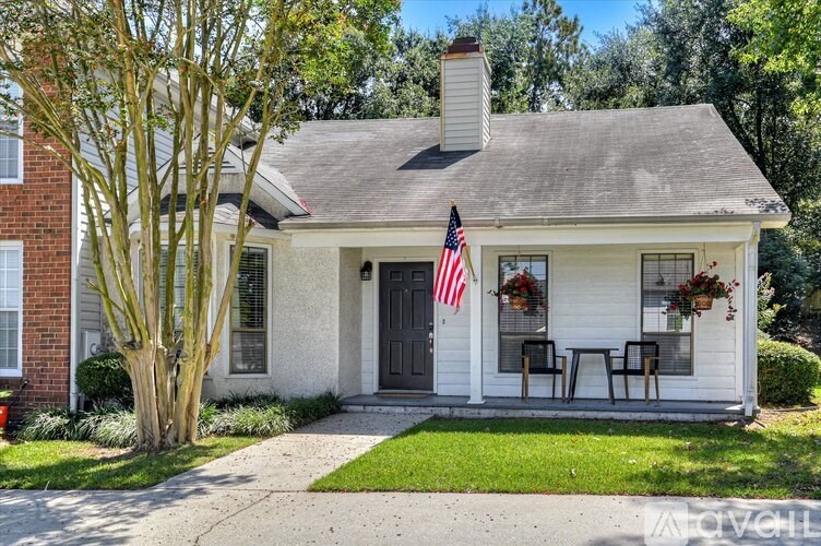 A small white house with a grey roof and a flag on the front door.