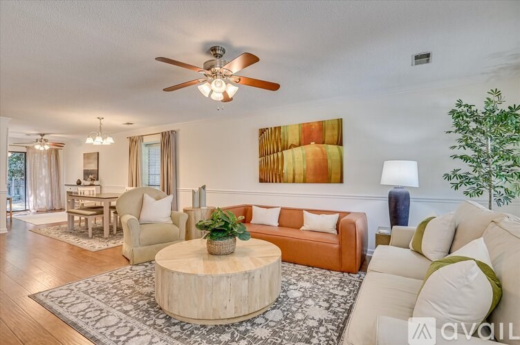A living room with a white couch, a wooden coffee table, and a ceiling fan.
