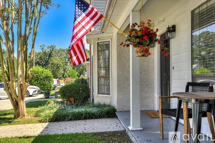 A house with a flag and a flower pot on the porch.