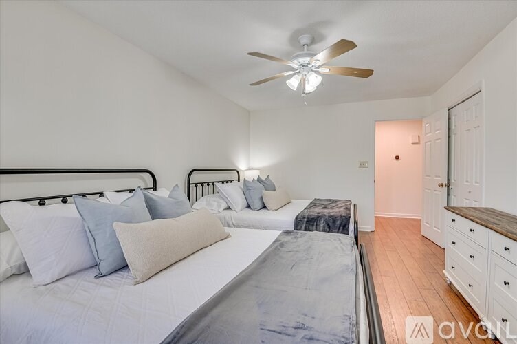 A bedroom with a bed, dresser, and ceiling fan.