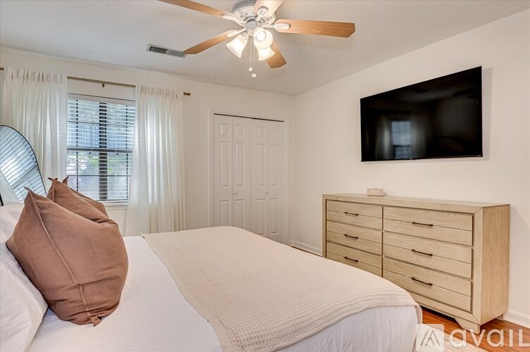 A bedroom with a bed, dresser, and a ceiling fan.