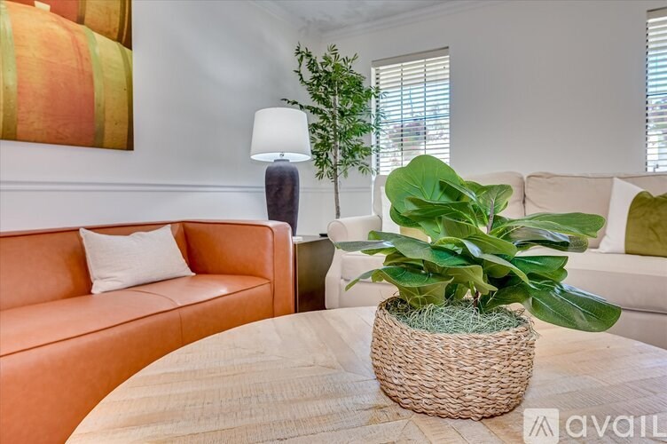 A living room with a couch, a table, and a potted plant.