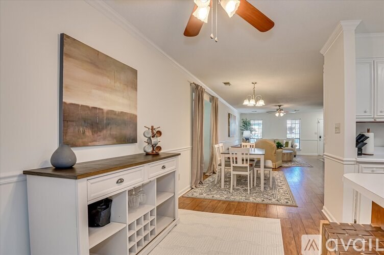 A modern kitchen with a large painting on the wall and a dining area in the background.