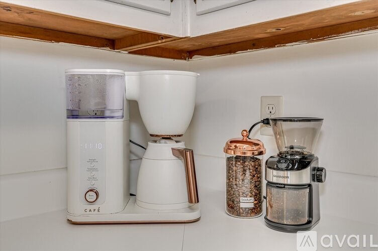A coffee maker, a French press, and a grinder are on a kitchen counter.