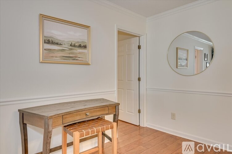 A room with a desk and chair and a painting on the wall.