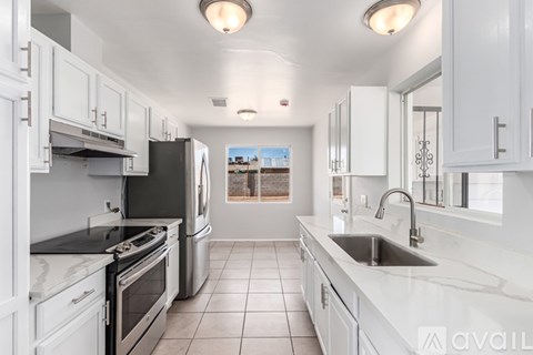 A kitchen with white cabinets and black appliances.