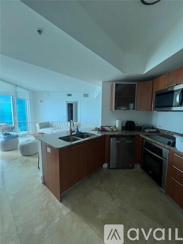 A kitchen with brown cabinets and a black dishwasher.