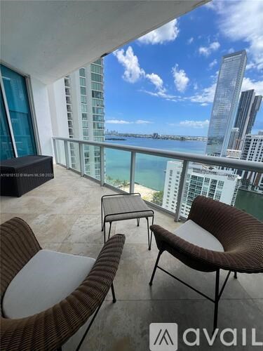 A balcony with chairs and a table overlooking the water.