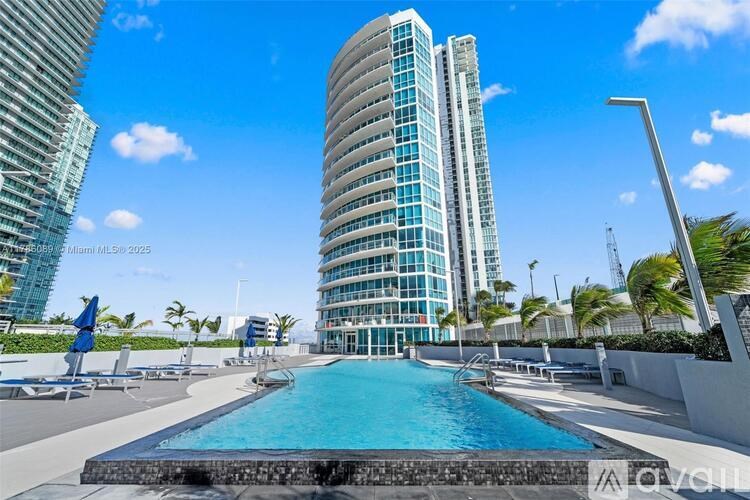 A pool in front of a tall building with palm trees in the background.