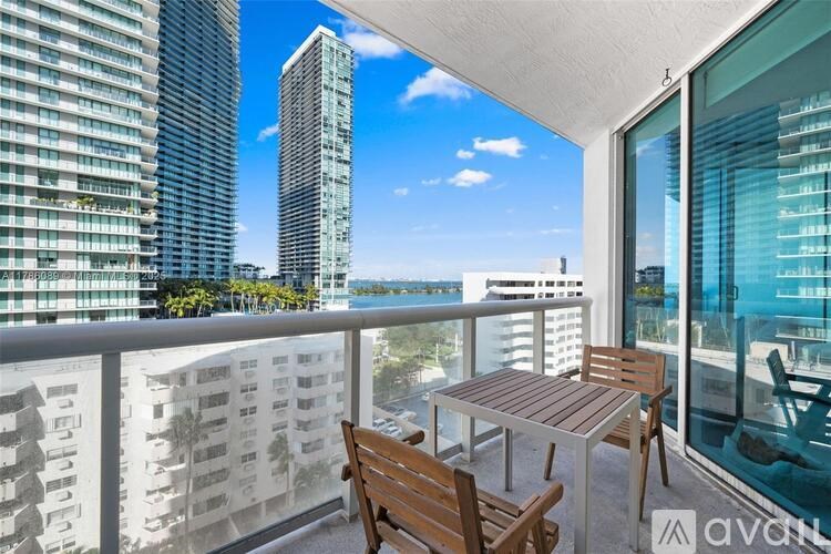 A balcony with a table and chairs overlooks a cityscape.