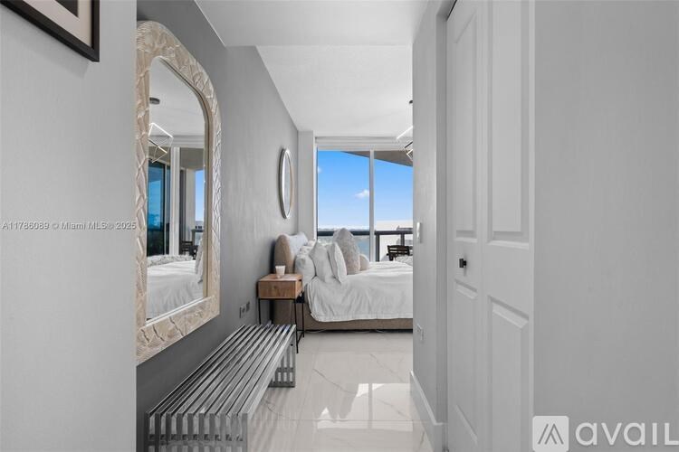 A bedroom with a large mirror and a bed with white bedding.