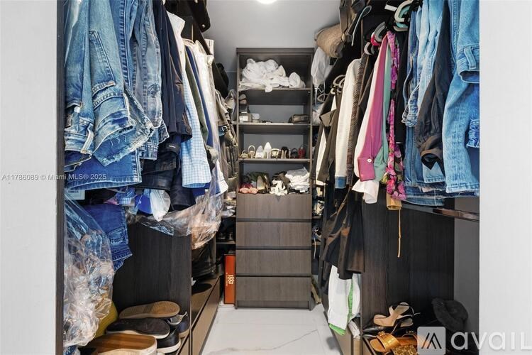 A cluttered walk-in closet with clothes and shoes.