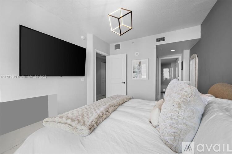 A bedroom with a large bed and a flat screen TV mounted on the wall.