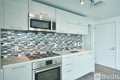 A modern kitchen with white cabinets and a tiled backsplash.