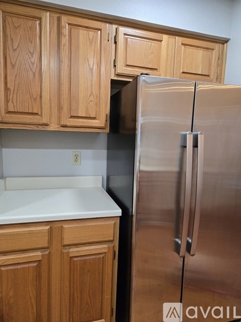 A kitchen with wooden cabinets and a stainless steel refrigerator.